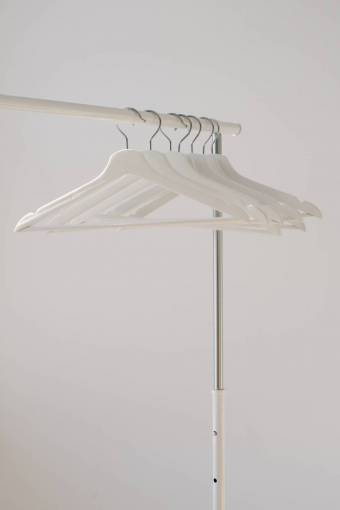 retail clothing close-up fashion hanging coat rack;hangers;dressing room;empty;white coathanger indoors