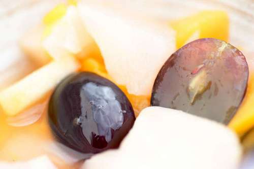 mixing Fresh and healthy tropical fruit salad with pieces of grapes, apples and peach