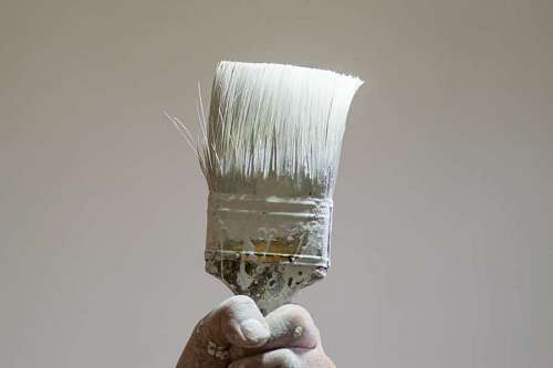 blanco y negro Mano sosteniendo un viejo pincel con pintura blanca