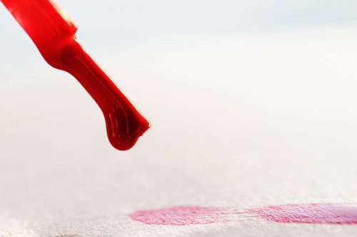 Little brush painting red lines on a white papper