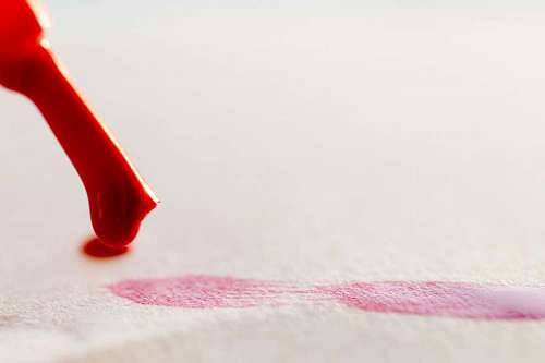 Little brush painting red lines on a white papper