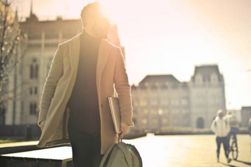 negocios Hombre de negocios elegante con laptop caminando en la ciudad