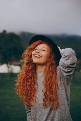 sunlight Young woman with reddish hair in curlers smiling outdoors