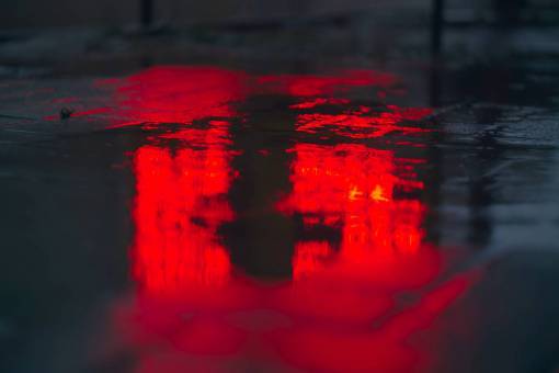 environment Reddish light reflected in a puddle of water on a street at night