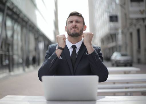 negocios Empresario frente a su computadora portátil con los ojos cerrados y expresión de deseo