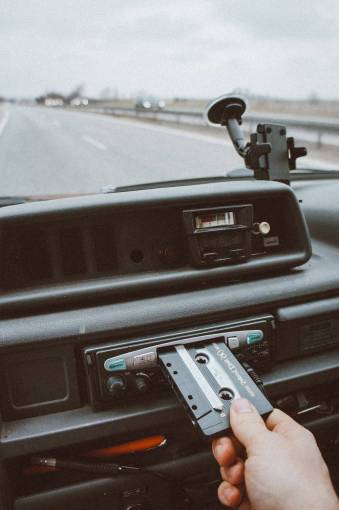 Una persona que inserta un casete de música en el reproductor del automóvil.