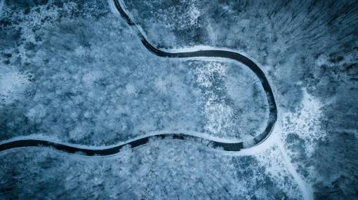 montanas nevadas Camino sinuoso en un bosque nevado, vista de drone