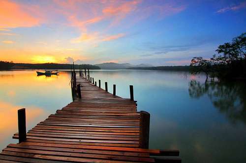 Muelle de madera frente a un hermoso lago al atardecer
