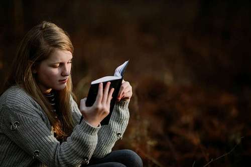 Mujer joven leyendo un libro al aire libre