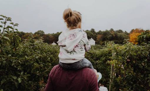 looking-over-shoulder Mother carrying her daughter on her shoulders