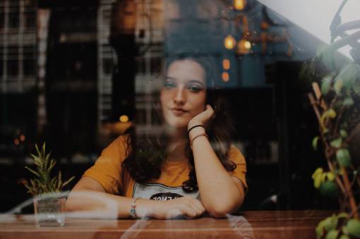 hembra Mujer joven sentada en un bar mirando por la ventana