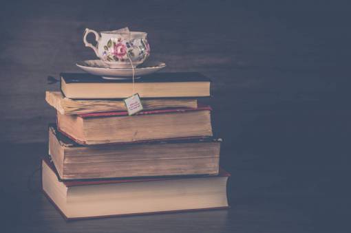 pila libro antiguo taza té bolsa de té mesa madera