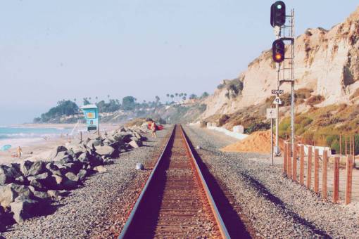 train tracks  pebbles  rocks  sand  beach  water  sky