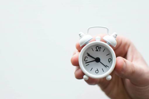 Hand holding clock on white background