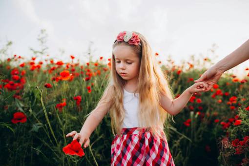 felicidad Madre cogida de la mano de su hija en un campo de amapolas