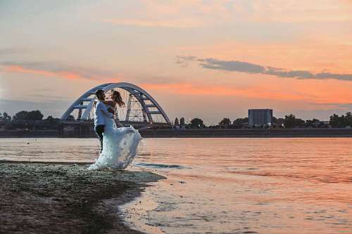 newlywed sea groom bride sunset newlyweds bridge hugging dawn evening ocean water exhilaration jumping happiness