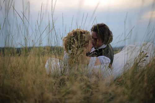 wife wife married laying grass husband hugging kiss field portrait  groom smiling