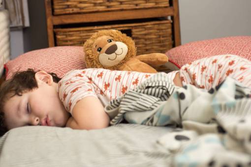 morning Little boy sleeping in his bed with teddy bear
