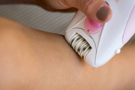 blanco Mujer afeitándose las piernas con máquina de depilación