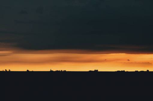 cielo naranja oscuro árboles negros montaña aventura