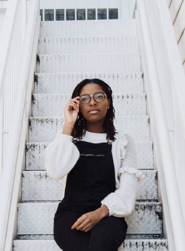 casual-clothing Portrait of a woman with glasses sitting on a ladder