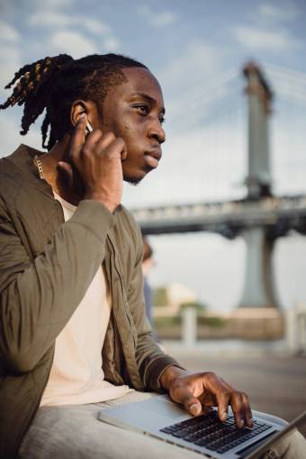 technology Young man with his laptop listening to music with wireless headphones