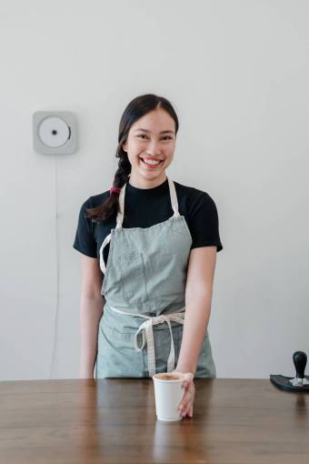 casual-clothing Young smiling woman serving coffee in a cafe