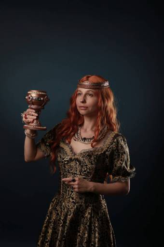 personas Mujer con traje medieval haciendo un puente con una copa de metal