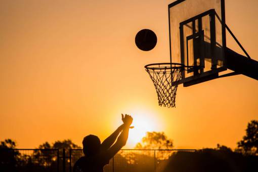 silhouette Man shooting basketball hoop at sunset