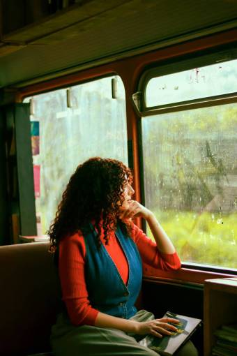 animals Adult woman on the train looking at the rain out the window while holding a book