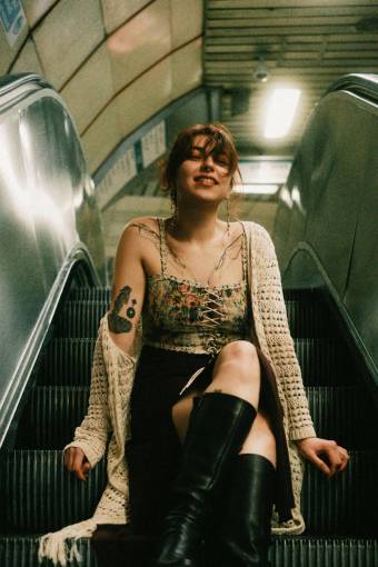 one-young-woman-only Young woman with tattoos sitting on an escalator looking at the camera