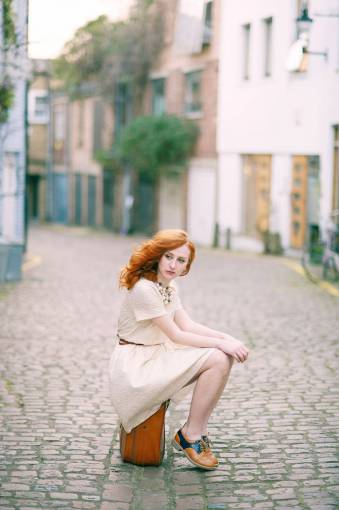 daylight fashion  model  sitting  suitcase  street  cobbles  red haor