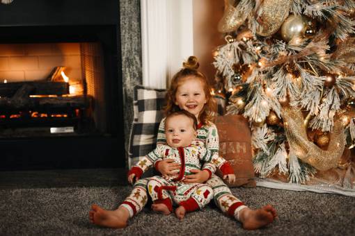 Little children posing for a photo next to the christmas tree