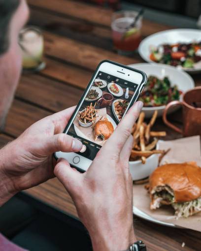 hipster Hombre tomando fotos de un plato de hamburguesas con teléfono móvil