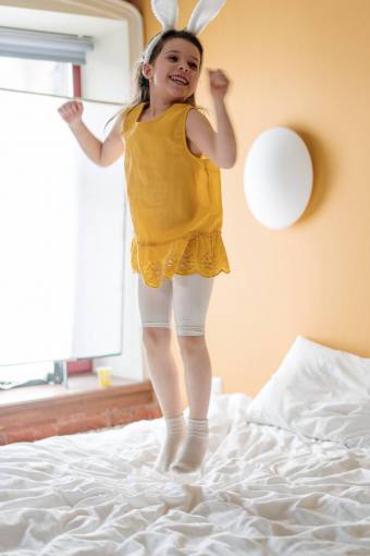 girl cute caucasian ethnicity girl;jumping;bed;yellow one person smiling child indoors