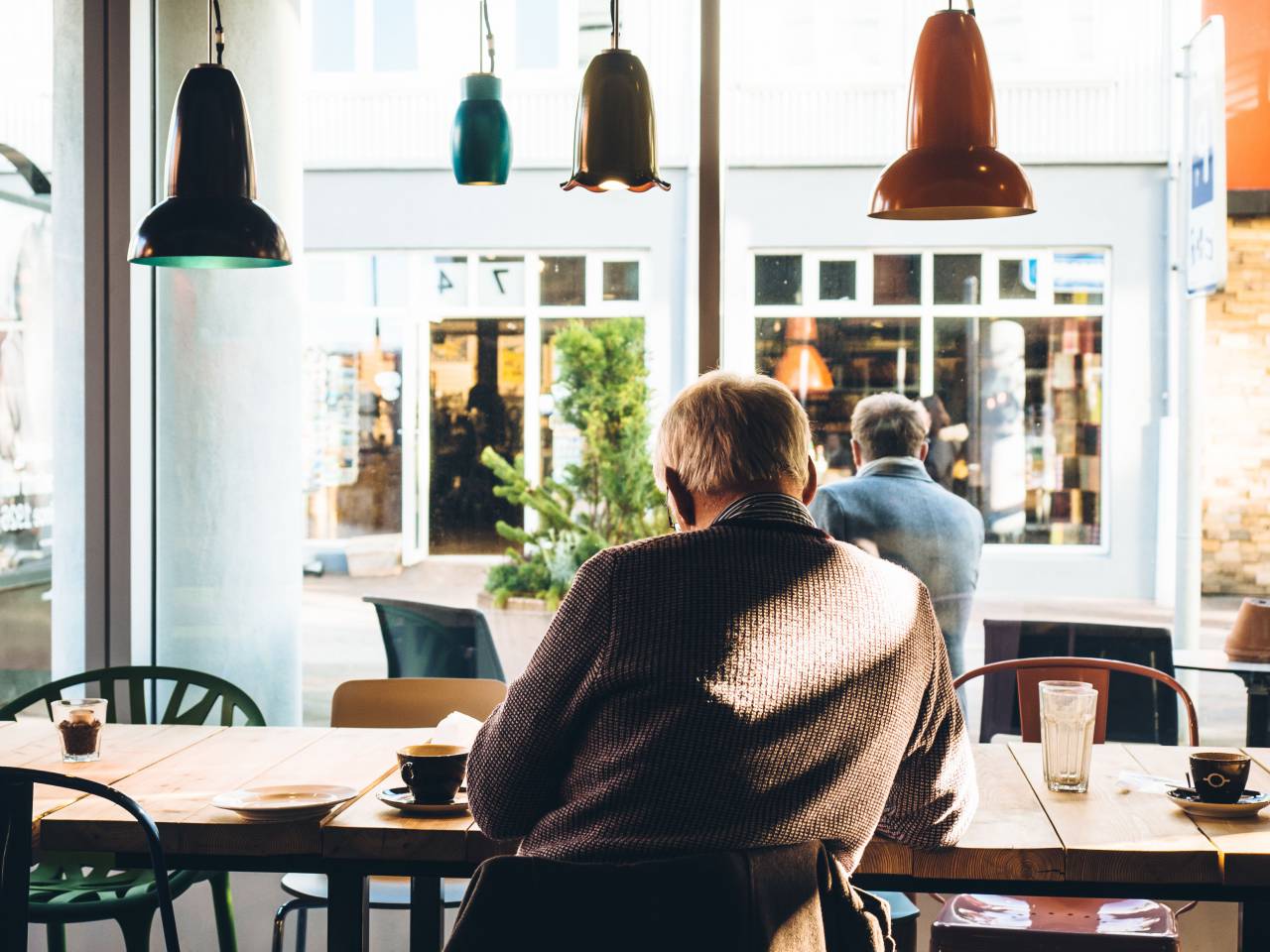 coffee, cafe, shop, espresso, mocha, latte, cappuccino, table, chairs, drink, glass, food, lights, windows, reading, old man, elderly, sweater
, 