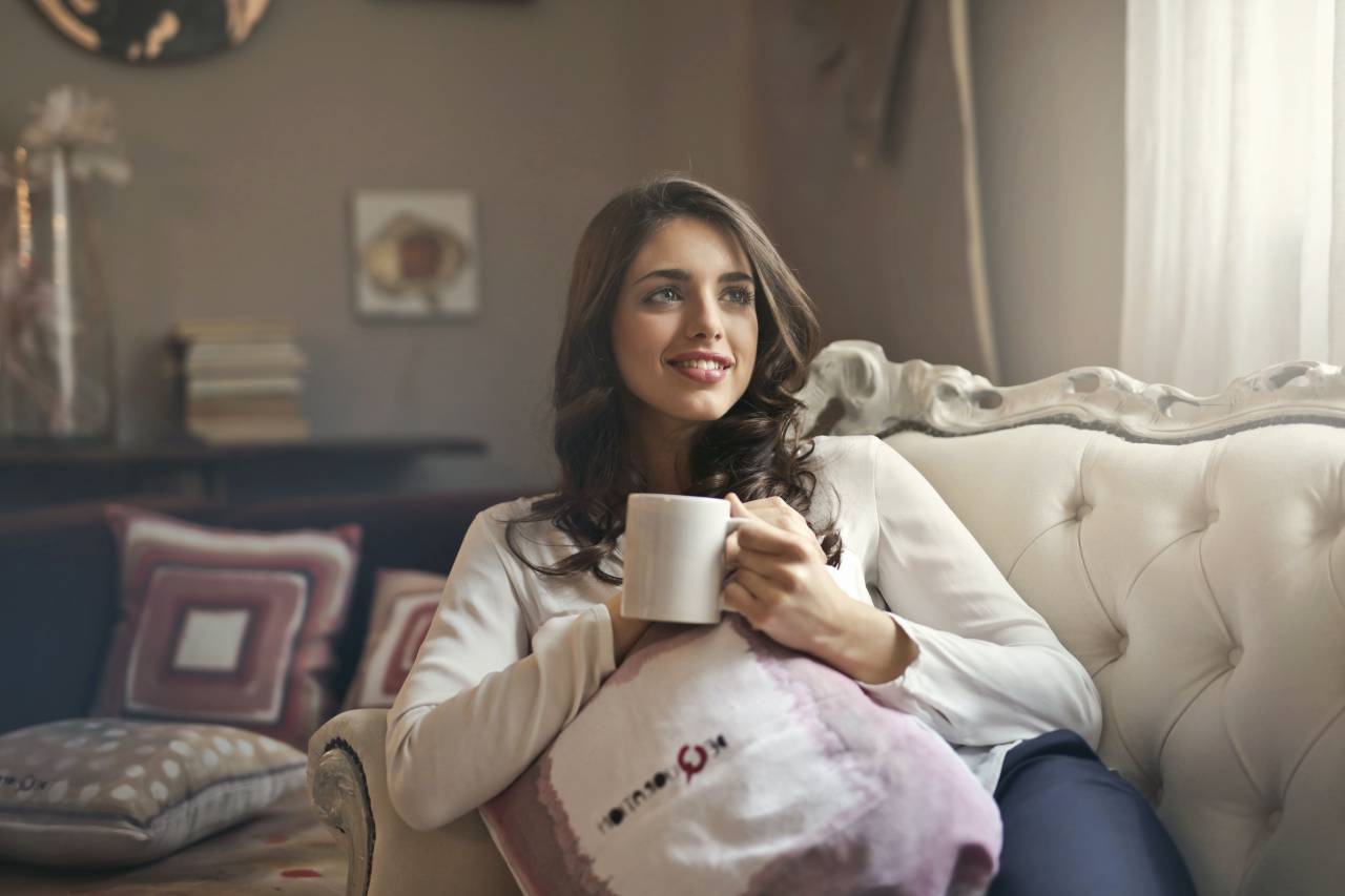 Young Woman, Coffee, Cup, Leaning, Couch, Relaxing, Comfort, Lifestyle, Morning, Beverage, Hot Drink, Casual, Cozy, Relaxation, Contentment, Enjoyment, Rest, Home, Indoor, Happiness, Smiling, 