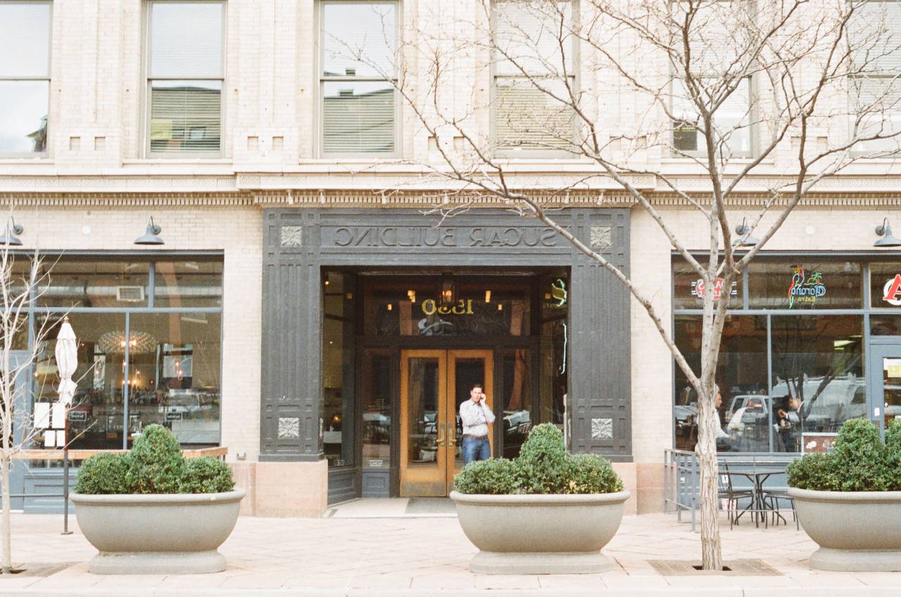 building, man, phone, talking, restaurnts, trees, plants, sidewalk, windows, stones, signs
, 