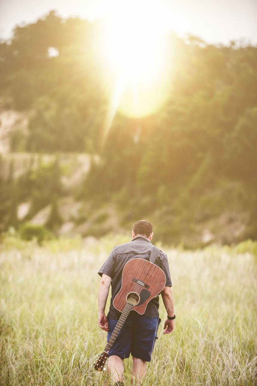 chico, hombre, macho, gente, espalda, caminar, salir, campo, césped, guitarra, música, instrumento, músico, artista, naturaleza, árboles, sol, rayos, deslumbramiento, luz, todavía, bokeh,