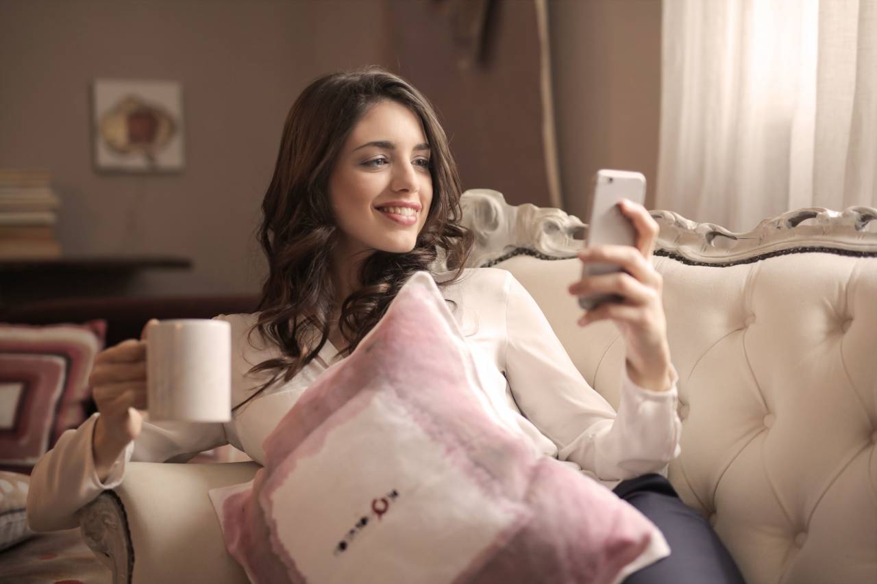Bonita, mujer, sonrisa, sofá, hogar, casa, café, móvil, teléfono, dispositivo, tecnología,