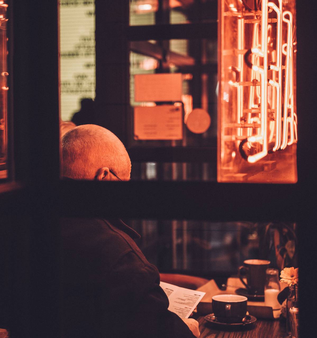 people, man, old, back, cup, coffee, cafe, restaurant, establishment, table, glass, wooden, paper, reading, sitting, signage
, 