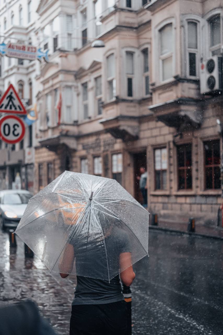 mujer;paraguas,lluvia,paraguas,al aire libre,húmedo,vida de la ciudad,clima,hombres,adulto,edificio exterior,una persona,mujer,caminar,gota de lluvia,arquitectura,paisaje urbano,caída,