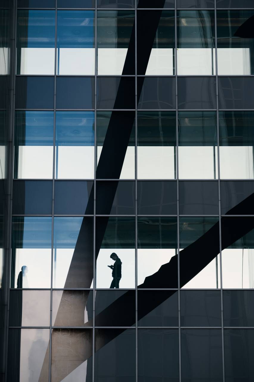 moderno;edificio;reflexión;una persona,arquitectura,ventana,hombre de negocios,hombres,estructura construida,moderno,silueta,exterior del edificio,vidrio,material,negocios,rascacielos,reflexión,éxito,adulto,azul,vida de la ciudad,persona de negocios,uno persona,trabajando,negocios corporativos,futurista,caminando,abstracto,