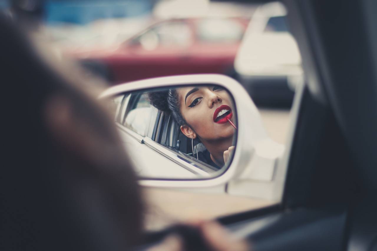woman;rear view mirror,car,women,young adult,driving,adult,beauty,lifestyles,transportation,one person,land vehicle,caucasian ethnicity,females,mode of transport,outdoors,looking,elegance,travel,smiling,fashion,young women,men,brown hair, 