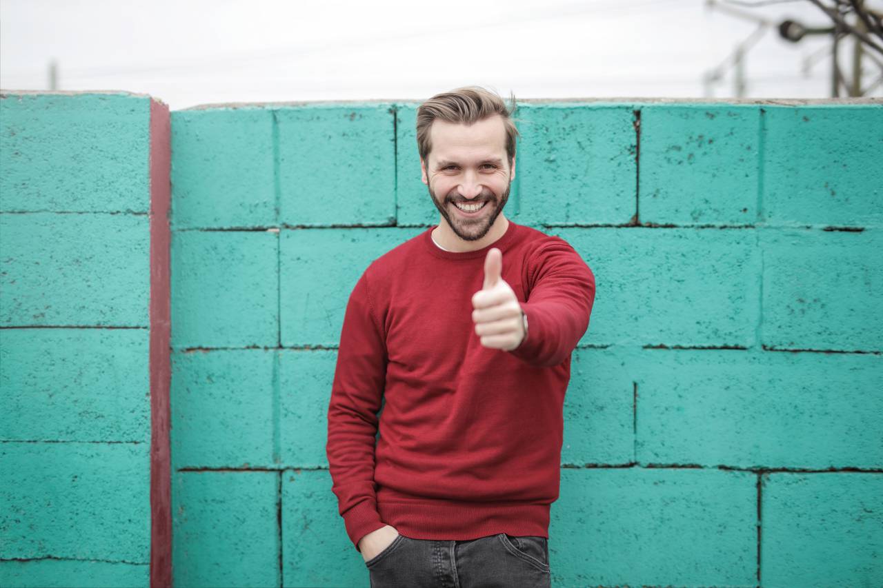 hombre, pulgares arriba, feliz, sonreír, rojo, jersey, jersey, azul, ladrillo, wall.jeans, fashio, macho, gente,