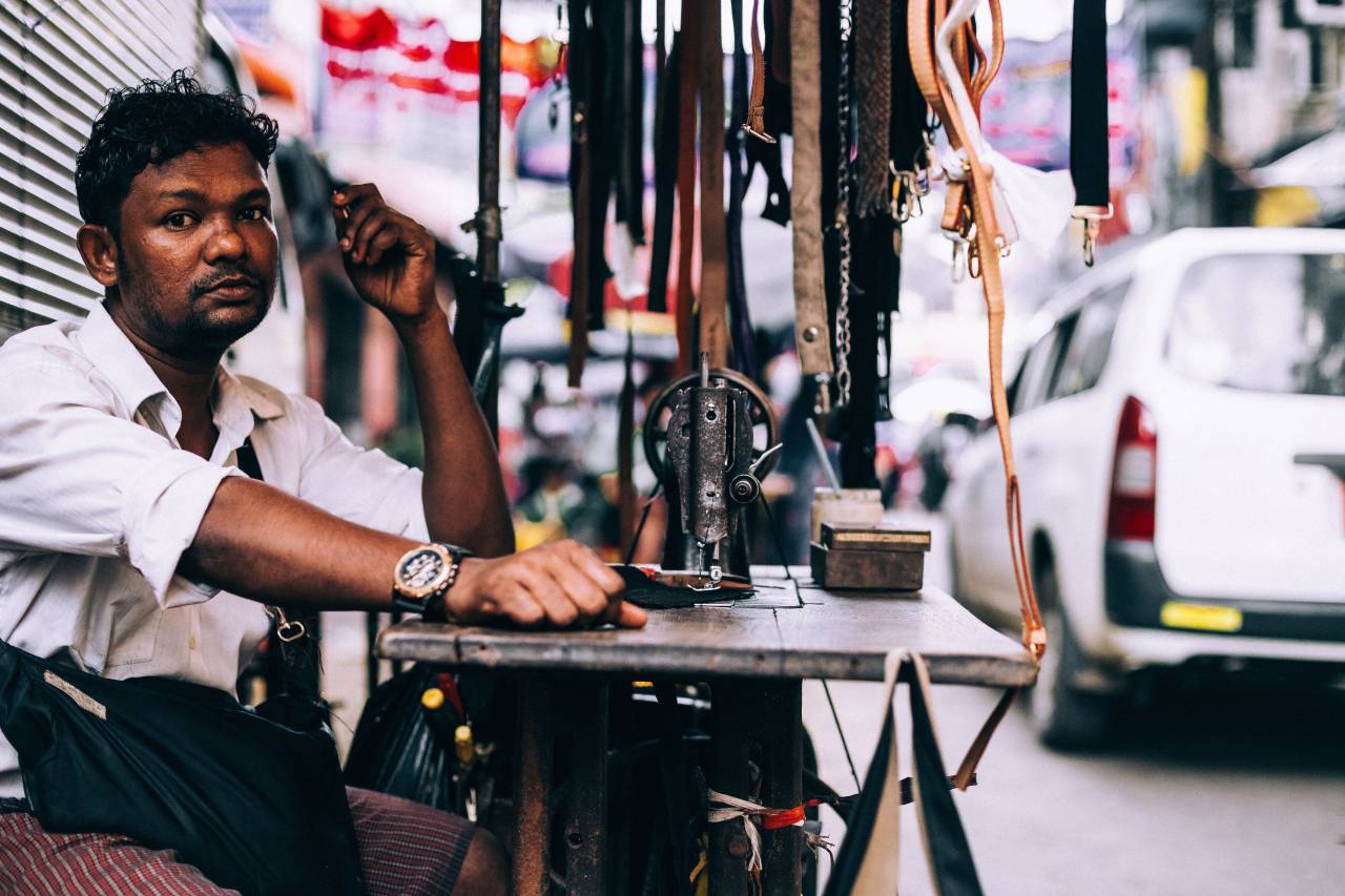 people, man, vendor, repair, accessories, belt, table, wood, dark skin, tone, curly
, 