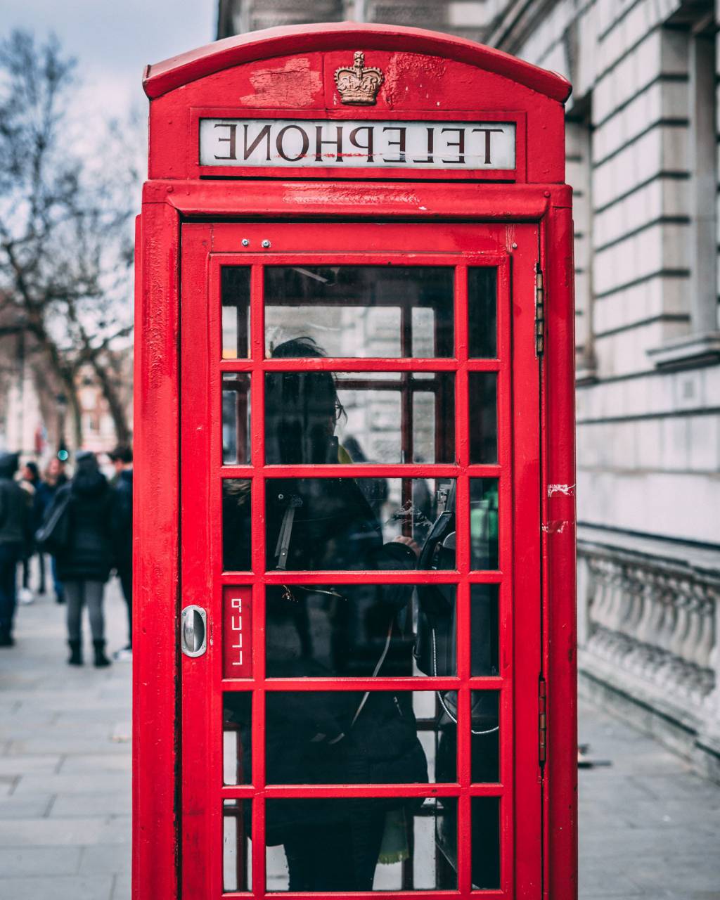 telephone booth;red;england,telephone booth,city life,telephone,outdoors,men,famous place,cultures,architecture,english culture,travel,british culture,capital cities,women,one person,tourism,adult,lifestyles,building exterior,communication, 