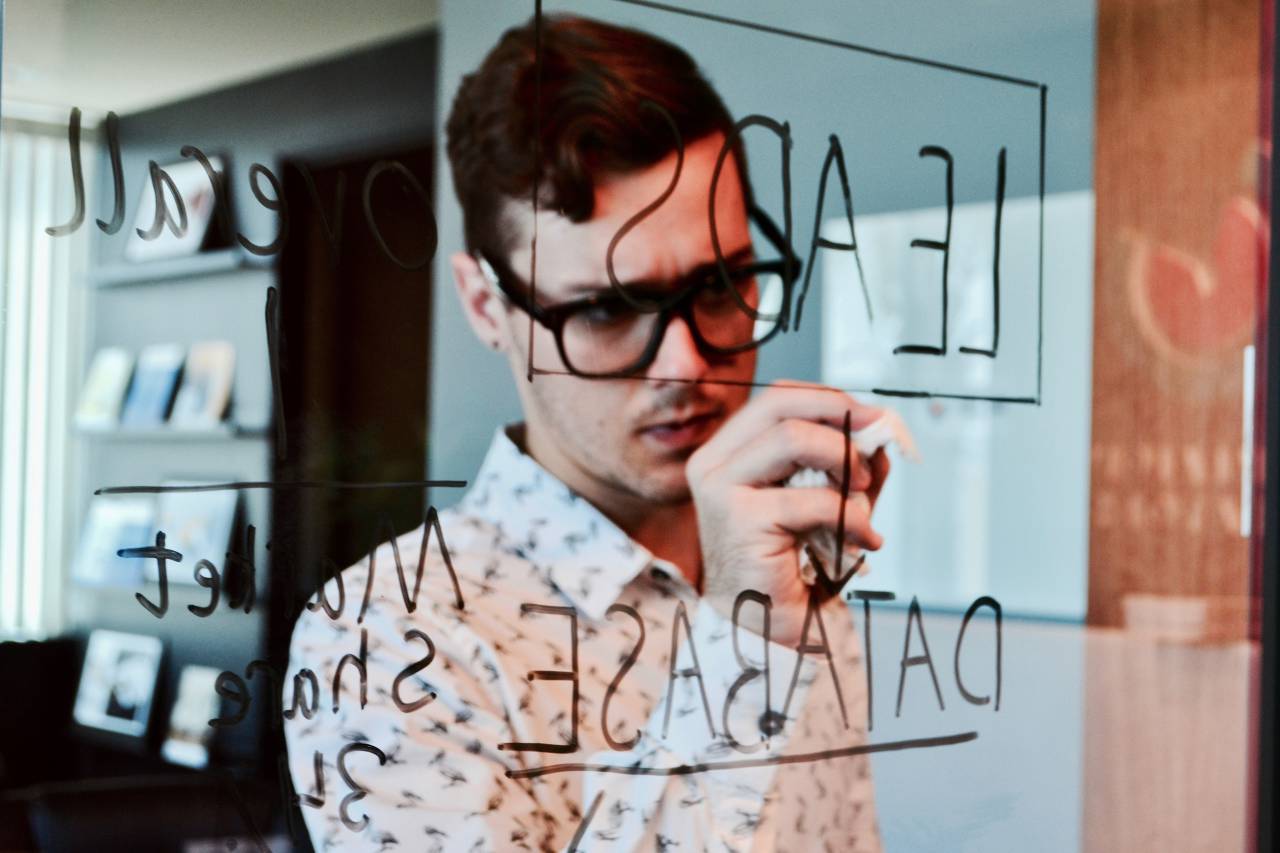 hombre;idea;Escritura;tablero,hombres,una persona,adulto,etnia caucásica,trabajando,hombre de negocios,interiores,varones,oficina,creatividad,persona de negocios,adulto joven,ocupación,buscando,negocios,anteojos,