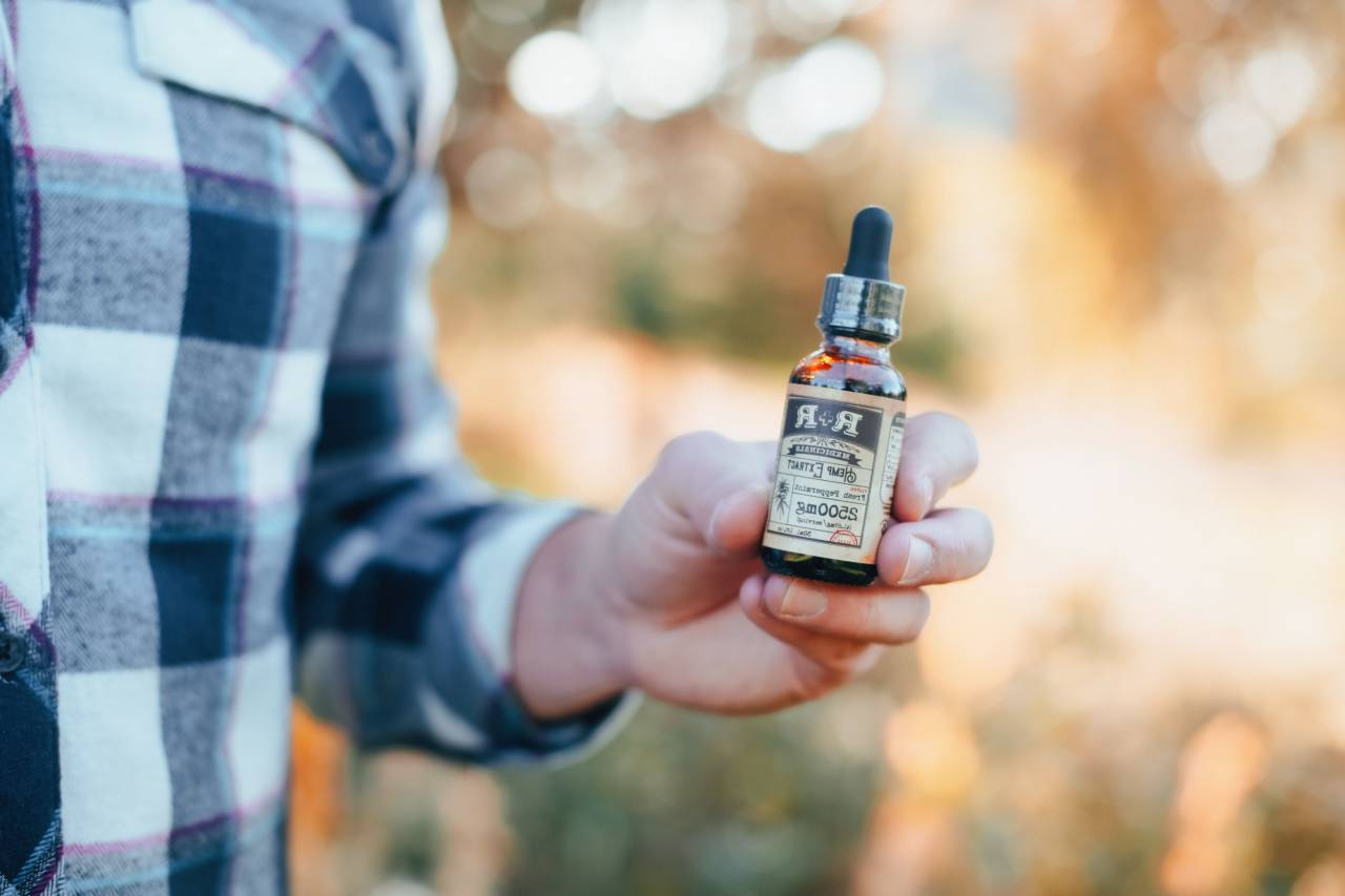 cannabis oil,men,human hand,outdoors,one person,close-up,adult,nature,caucasian ethnicity,lifestyles,holding,males,bottle,women, 