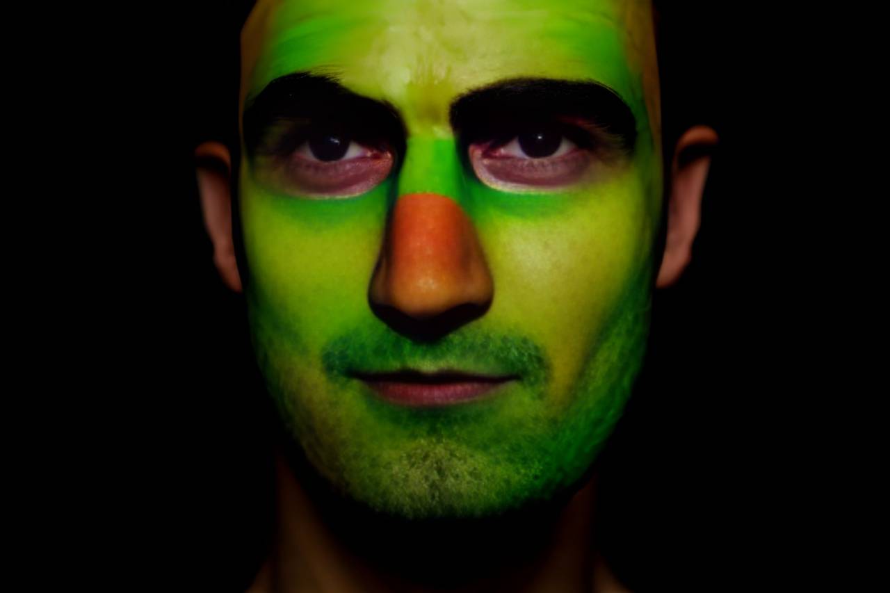 soccer;fan;brazil;painted;face,men,one person,human face,adult,portrait,caucasian ethnicity,looking at camera,face paint,close-up,black background,males,looking,young adult,studio shot,green color, 